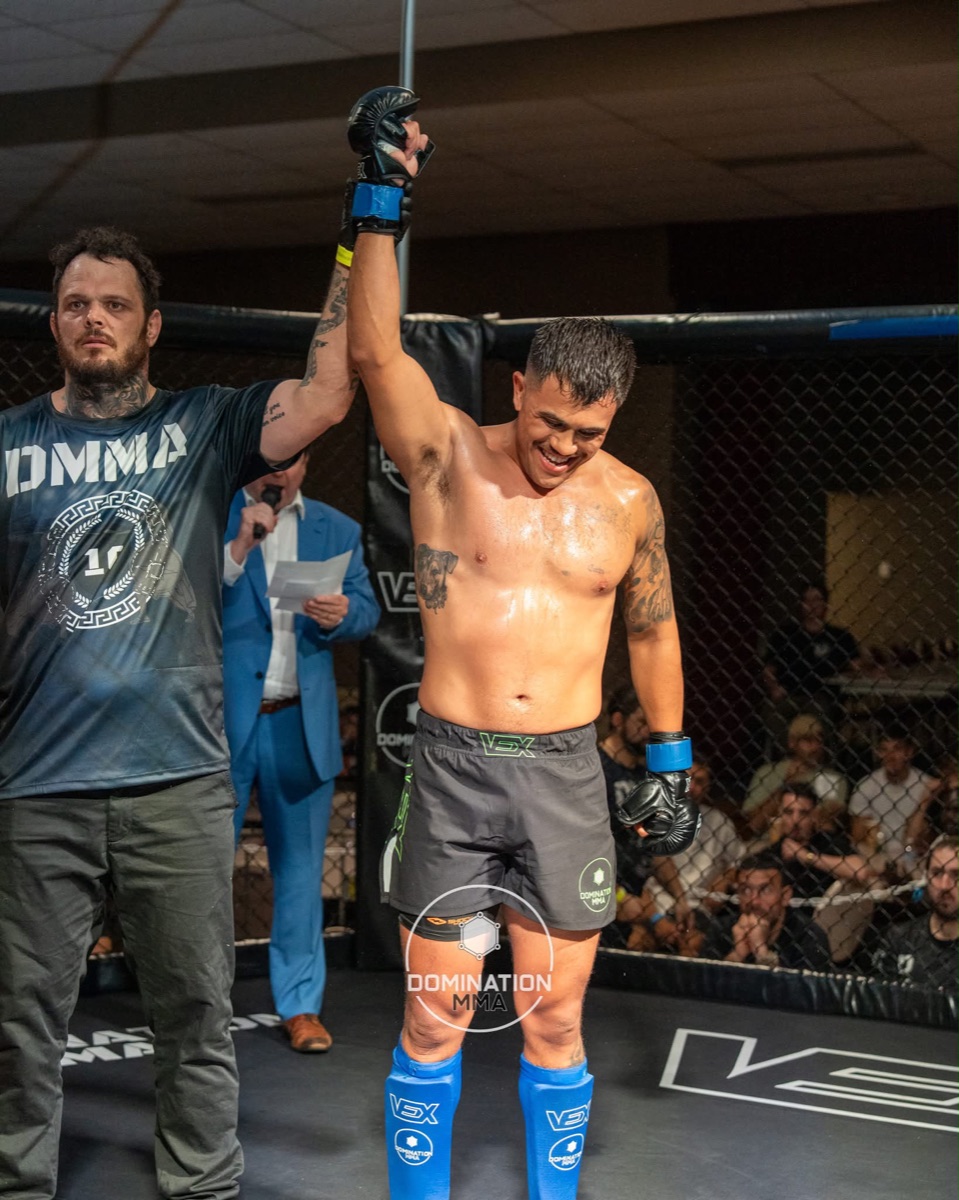 A DCA member smiles as his hand is raised after an MMA win